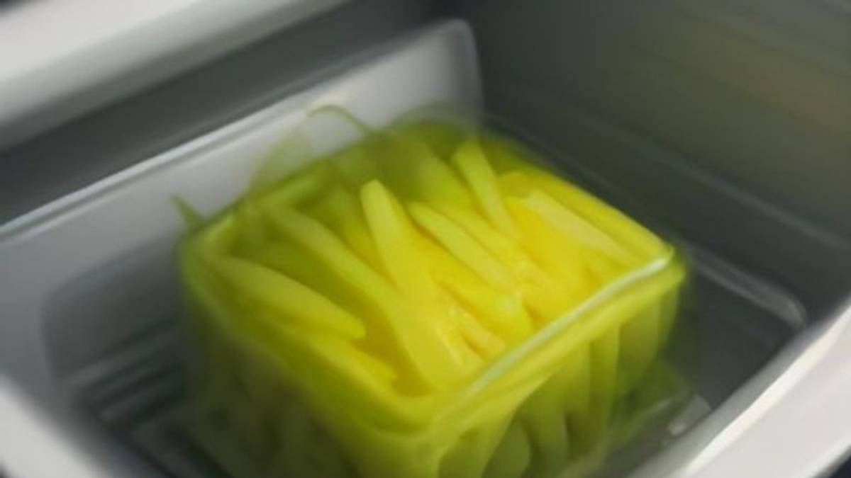 Руки укладывают вакуумный пакет с заготовкой в морозильную камеру